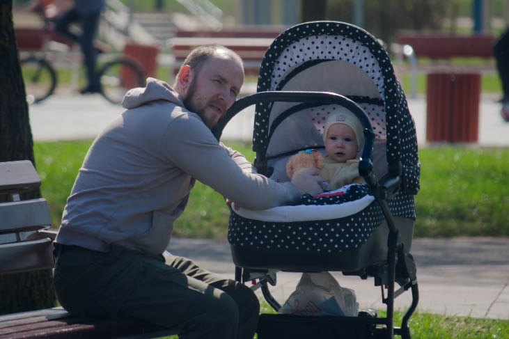 adobestock_206527872_opt.jpg Homme à genou devant un nouveau-né dans une poussette
